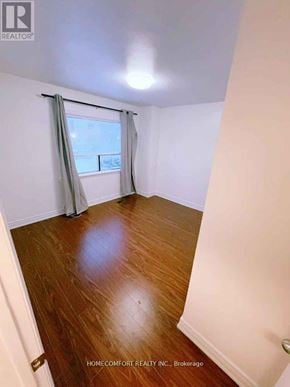 Toronto (Rexdale-Kipling) townhouse for rent - A room with wooden floors and a window with curtains.
