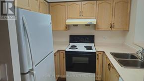 Toronto (Newtonbrook East) condo for rent - A kitchen with a white refrigerator, black stove, and wooden cabinets.