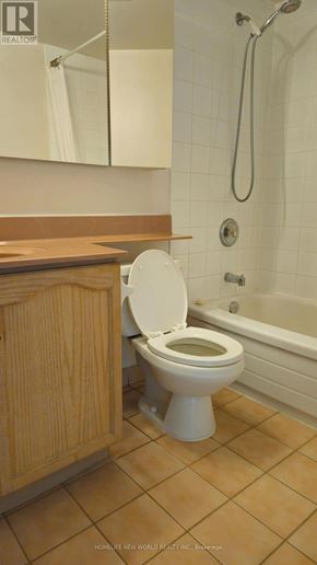 Toronto (Newtonbrook East) condo for rent - A white toilet in a bathroom with a wooden cabinet.