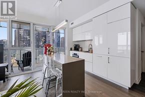 Toronto (Waterfront Communities) condo for rent - A modern kitchen with white cabinets and a view of the city.