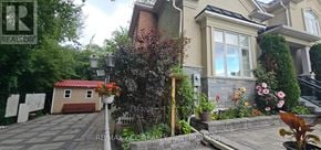 Toronto (Highland Creek) apartment for rent - A house with a red garage door is surrounded by greenery and plants.