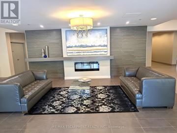 Hamilton (Durand) condo for rent - A living room with a grey couch and a black and white rug.