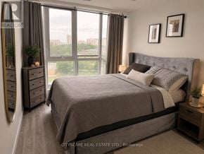 Waterloo condo for rent - A bedroom with a large bed, a dresser, and a window with a view of the city.