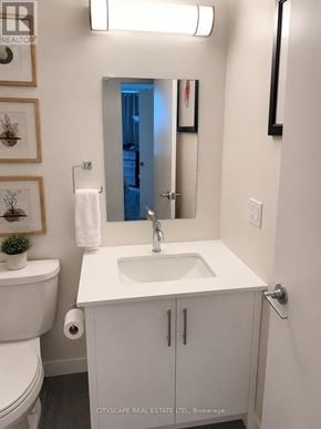 Waterloo condo for rent - A white bathroom with a toilet, sink, and mirror.