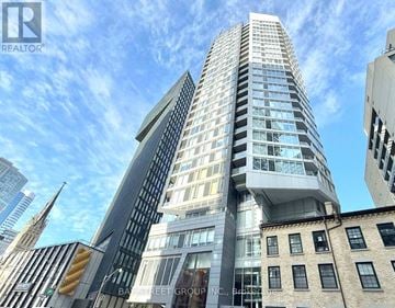 Toronto (Church-Yonge Corridor) condo for rent - A tall, modern building with many windows is the focal point of the image.