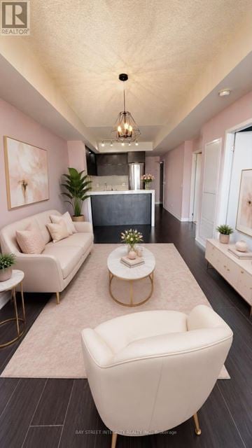 Toronto (Regent Park) condo for rent - A living room with a white sofa, a white armchair, and a coffee table with a plant on it.