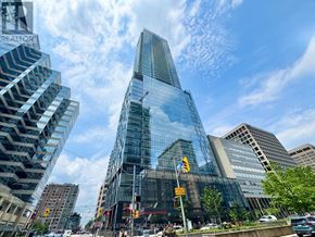 Toronto (Kensington-Chinatown) condo for rent - A tall glass building stands in the middle of a city intersection.