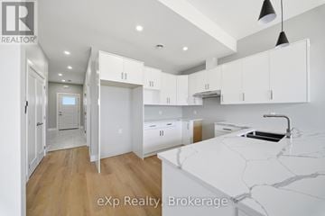 Quinte West (Trenton Ward) townhouse for rent - A kitchen with white cabinets and a marble countertop.