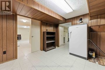 Ottawa apartment for rent - A white refrigerator is in a kitchen with wooden walls.