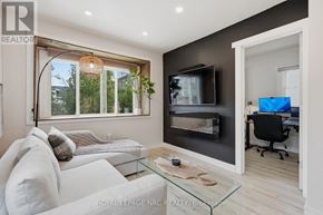 St. Catharines (Port Dalhousie) apartment for rent - A modern living room with a white couch, a glass coffee table, and a television.