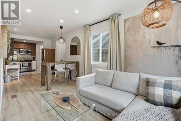 St. Catharines (Port Dalhousie) apartment for rent - A well-lit living room with a grey sofa and a glass coffee table.