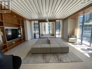Toronto (Mimico) townhouse for rent - A spacious living room with a large grey sofa and a television.
