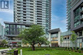 Toronto (Willowdale West) condo for rent - A modern building with glass windows and a tree in front of it.