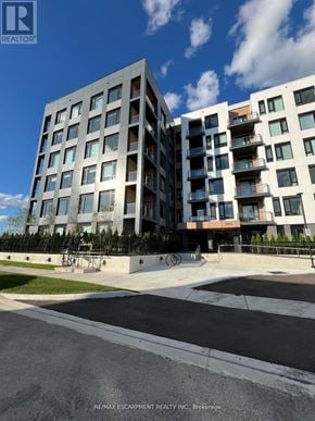 Milton (Fo Ford) condo for rent - A modern apartment building with a parking lot in front.