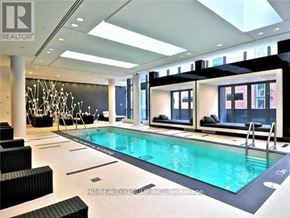 Toronto (Bay Street Corridor) condo for rent - A large indoor swimming pool with a black bench and a black chair.