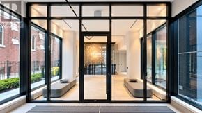 Toronto (North St. James Town) condo for rent - A modern entrance with a glass door and a bench inside.
