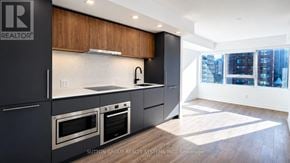 Toronto (North St. James Town) condo for rent - A modern kitchen with stainless steel appliances and wooden cabinets.