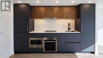Toronto (North St. James Town) condo for rent - A modern kitchen with dark cabinets and stainless steel appliances.