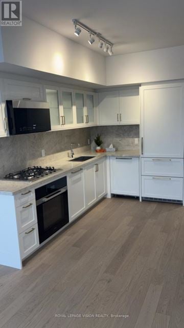 Toronto (Englemount-Lawrence) condo for rent - A kitchen with white cabinets and a wooden floor.