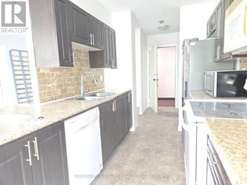 Toronto (Malvern) condo for rent - A kitchen with dark cabinets and a white dishwasher.