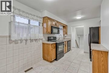 Mississauga (Erindale) apartment for rent - A kitchen with wooden cabinets and a black refrigerator.