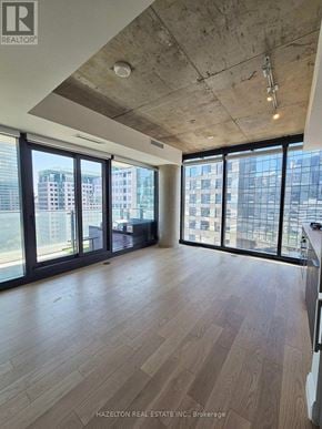 Toronto (Waterfront Communities) condo for rent - A room with wooden flooring and large windows overlooking a cityscape.