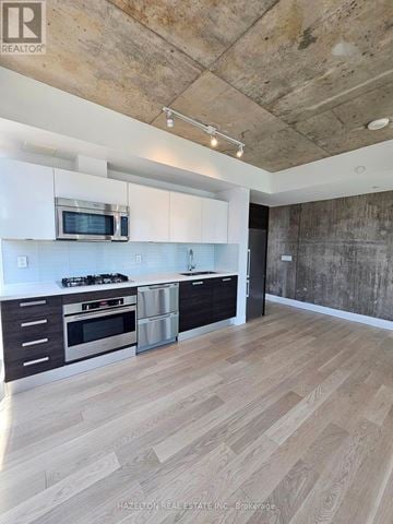Toronto (Waterfront Communities) condo for rent - A modern kitchen with wooden floors and a concrete wall.