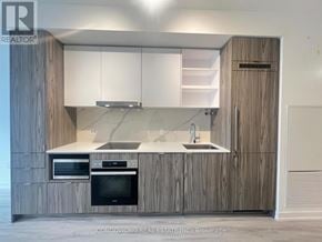 Toronto (Waterfront Communities) condo for rent - A modern kitchen with wooden cabinets and a marble countertop.