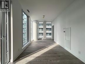 Toronto (Waterfront Communities) condo for rent - A long hallway with white walls and wood flooring.