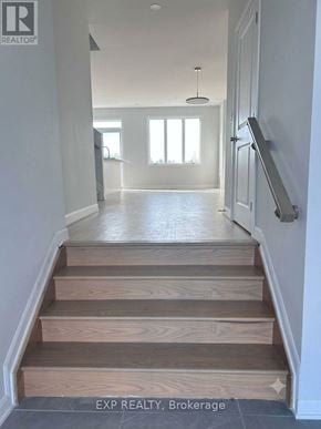 Ottawa townhouse for rent - A hallway with wooden stairs leading to a bright room.