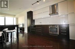 Toronto (Bay Street Corridor) condo for rent - A modern kitchen with dark wood floors and white cabinets.