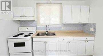 Niagara Falls (Hospital) apartment for rent - A white kitchen with a stove, sink, and cabinets.