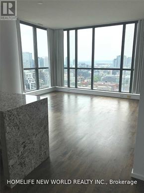 Toronto (Waterfront Communities) condo for rent - A large, empty room with a view of the cityscape outside the windows.