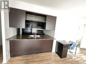 Toronto (Bendale) condo for rent - A kitchen with a brown countertop and a black fridge.