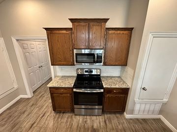 Temple triplex for rent - A kitchen with wooden cabinets and a granite countertop.