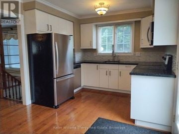 Oshawa (Vanier) apartment for rent - A kitchen with a black fridge and white cabinets.