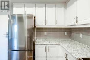 Niagara Falls (Hospital) condo for rent - A kitchen with a stainless steel refrigerator and white cabinets.
