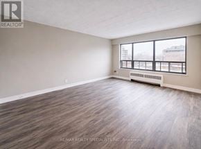 Toronto (South Parkdale) condo for rent - A spacious room with wood flooring and a large window.