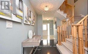 Milton (De Dempsey) townhouse for rent - A hallway with a wooden staircase and a table with a vase on it.