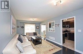 Milton (De Dempsey) townhouse for rent - A living room with a couch, coffee table, and a kitchen area in the background.