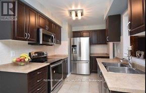 Milton (De Dempsey) townhouse for rent - A kitchen with brown cabinets and a stainless steel refrigerator.
