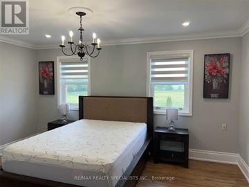 New Tecumseth apartment for rent - A bedroom with a large bed and a chandelier.