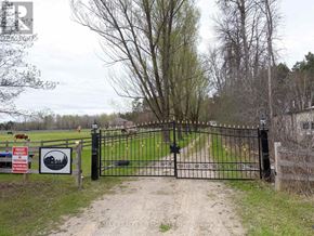 New Tecumseth apartment for rent - A black gate with a sign that says "No Trespassing" in front of a field.