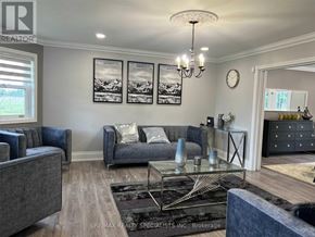 New Tecumseth apartment for rent - A living room with a grey couch, a glass coffee table, and a chandelier.