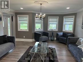 New Tecumseth apartment for rent - A living room with a grey couch, a glass coffee table, and a chandelier.