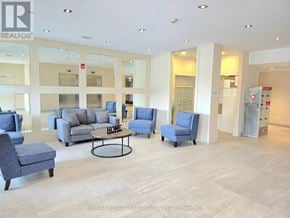 Burlington (Tansley) condo for rent - A spacious living room with a variety of furniture including a grey sofa, blue armchair, and a black coffee table.