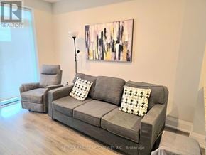 Burlington (Tansley) condo for rent - A grey couch with a pillow and a painting on the wall.