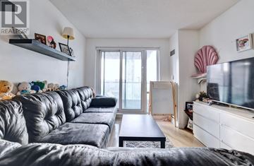 Mississauga (City Centre) condo for rent - A living room with a black leather couch and a flat screen TV.