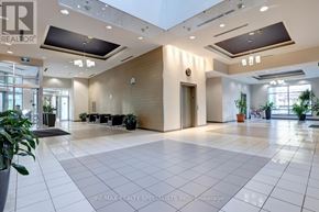 Mississauga (City Centre) condo for rent - A spacious lobby with a white tile floor and a variety of potted plants.