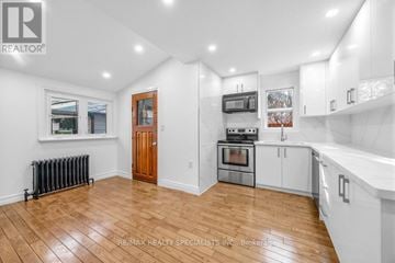 Toronto (Briar Hill-Belgravia) apartment for rent - A spacious kitchen with white cabinets and a wooden door.